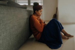 A woman who is feeling the psychological impact of DUI charges sitting on the floor with her hands across her chest