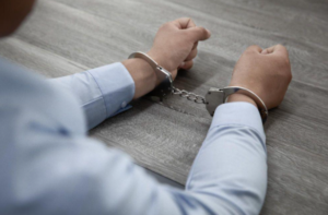 Person with handcuffs on hand after being charged with drug possession.