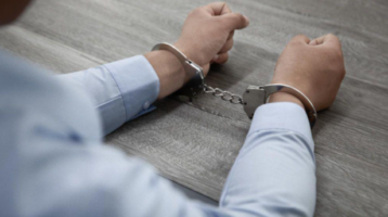 Person with handcuffs on hand after being charged with drug possession.